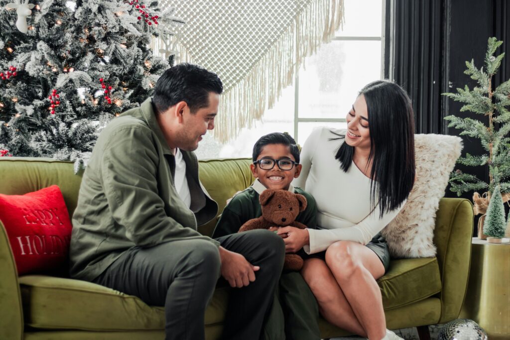 Happy family (two adults and a child) sitting on a couch, representing Colorado first-time homebuyers achieving their dream with the right credit score.