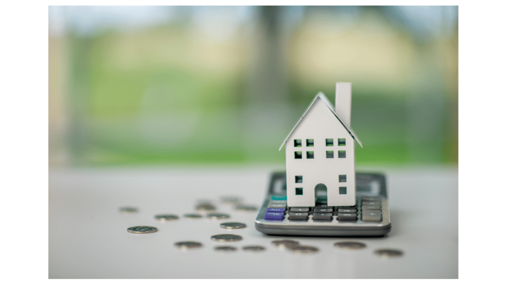 Model house on calculator with scattered coins, representing rental income and DSCR loan qualification in Colorado