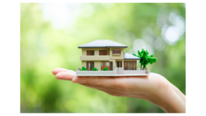 A hand holding a miniature model of a house against a blurred green background, symbolizing real estate investment and growth.